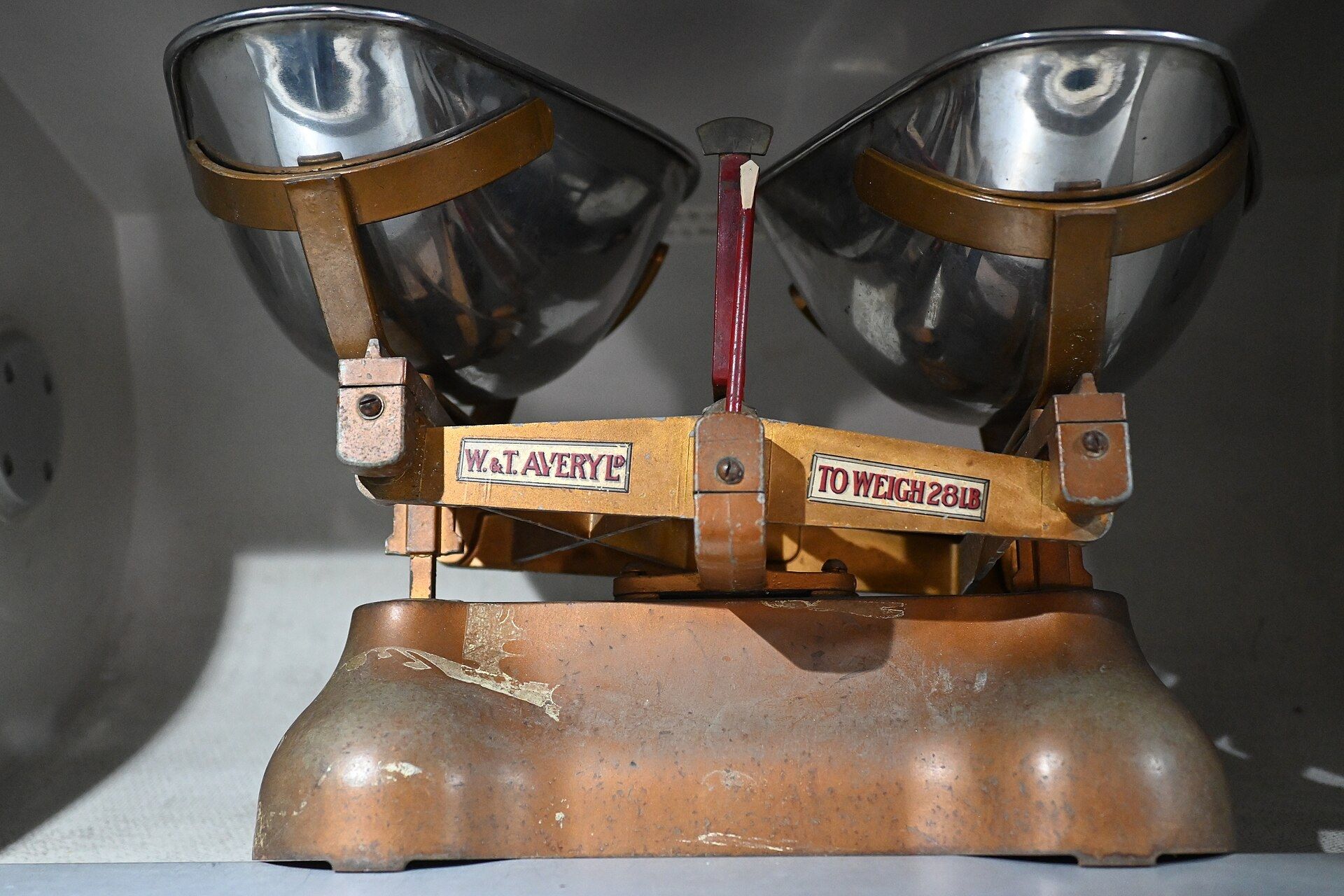 An antique two pan balance scale with worn brass base and metal bowls. A Wikimedia Commons photograph on Brent O'Mara Insights.