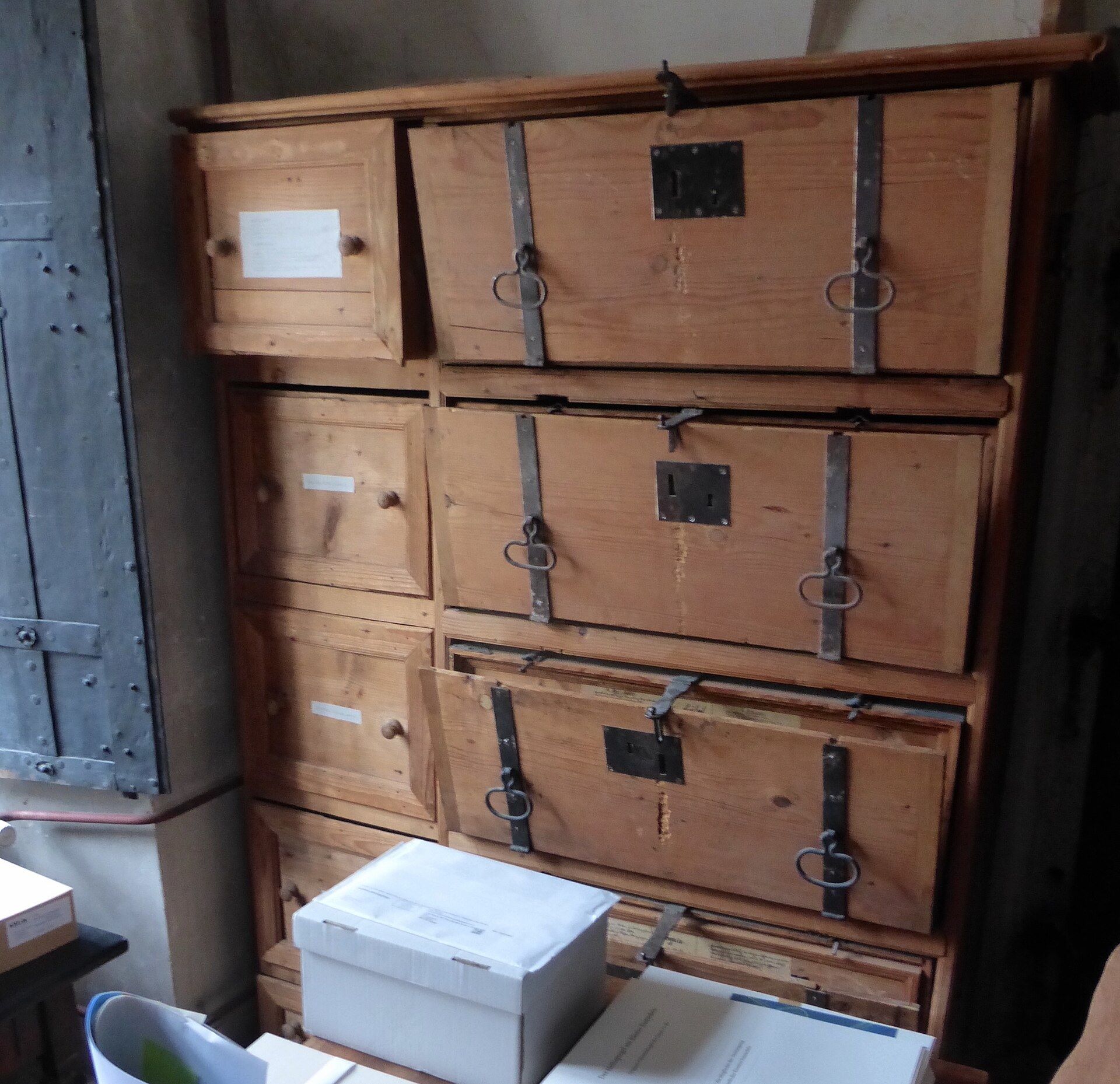 Old wooden archive boxes stacked on shelves in an abbey record room. A Wikimedia Commons photograph on Brent O'Mara Insights.