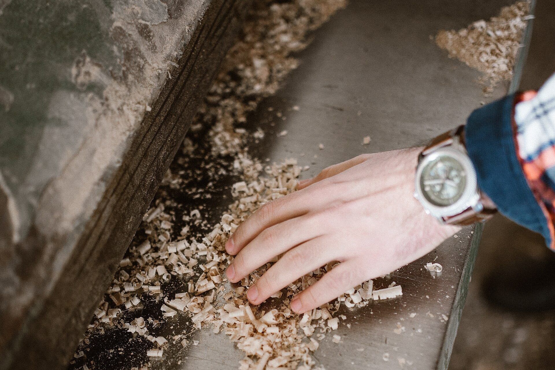 A hand sifting wood shavings on a workshop bench. A Wikimedia Commons photograph on Brent O'Mara Insights.